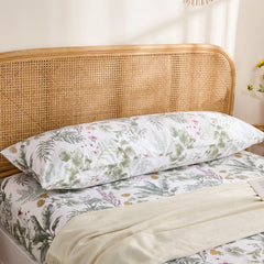 The cotton tropical leaf print body pillowcase placed horizontally against a rustic rattan headboard.