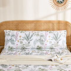 Full front view of a long cotton body pillowcase with a detailed green and pink tropical jungle print, displayed on a bed.
