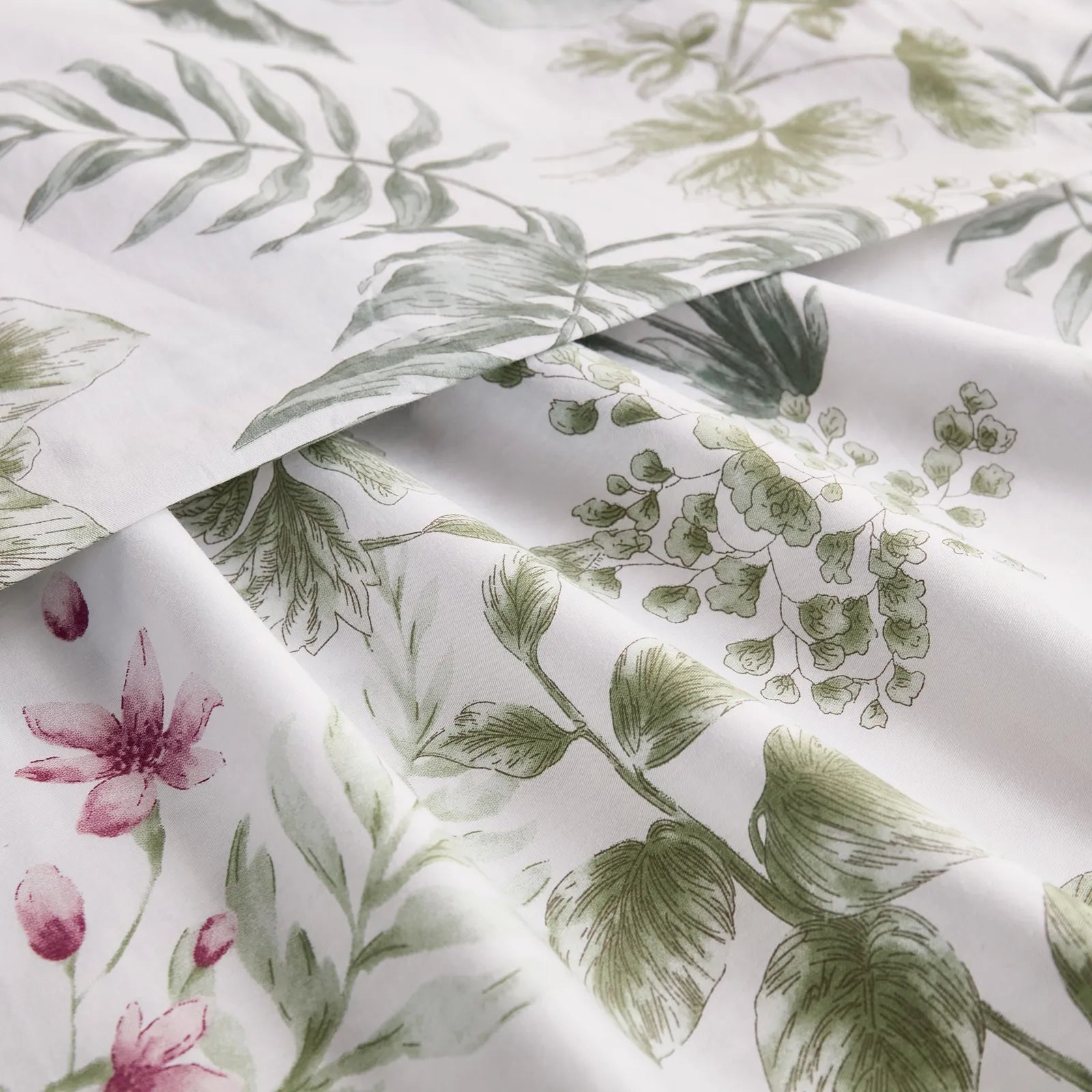 Extreme close-up of the cotton fabric, showing the texture and the detailed green and pink tropical foliage pattern.