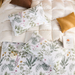 Overhead view of two cotton tropical print pillowcases on a white quilted duvet with contrasting pillows.