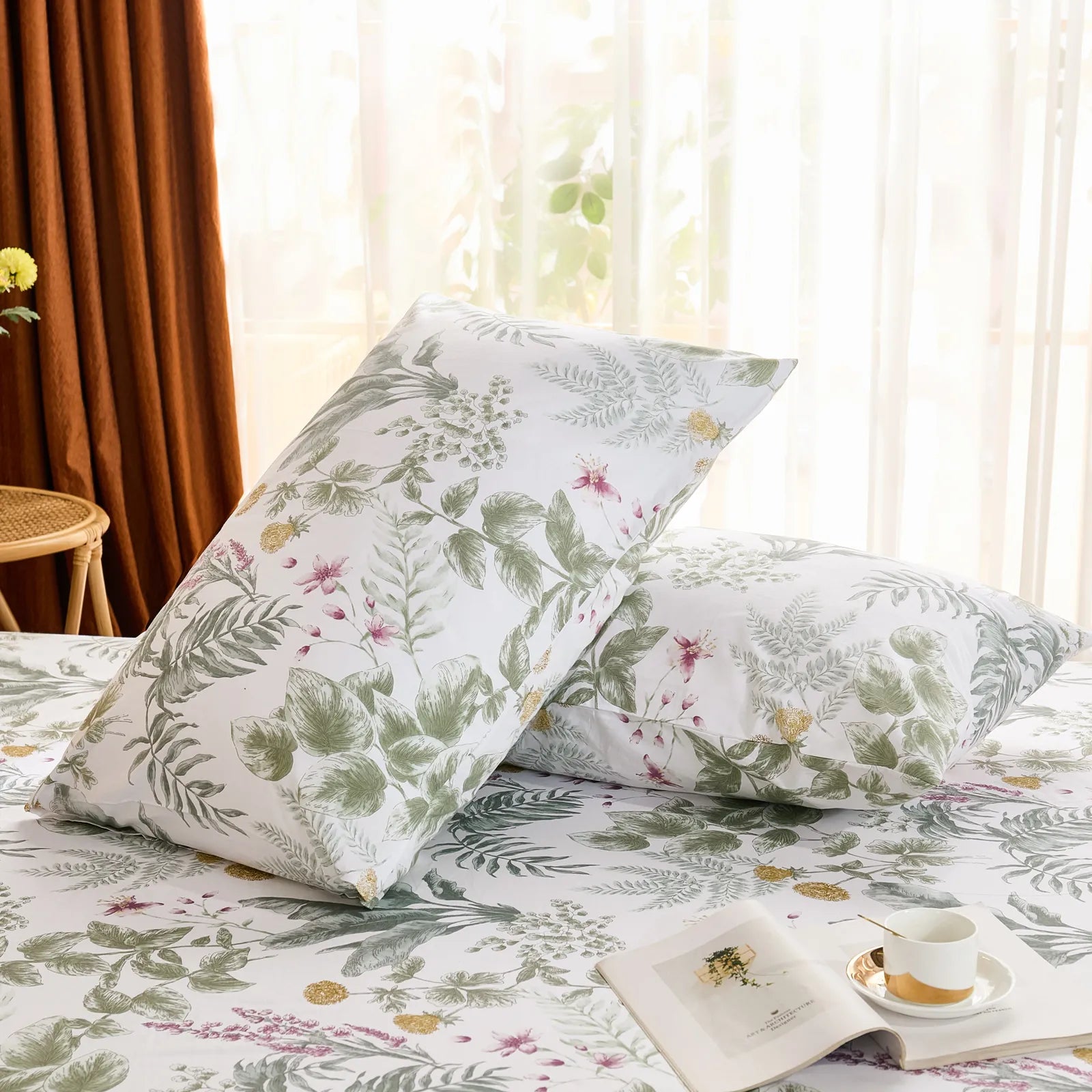 Two cotton pillowcases with a vibrant green and white jungle print, brightly lit by natural light near a window.