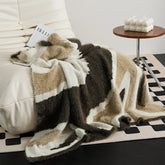 Abstract fluffy knit throw blanket in mocha and warm taupe draped on white leather Togo sofa