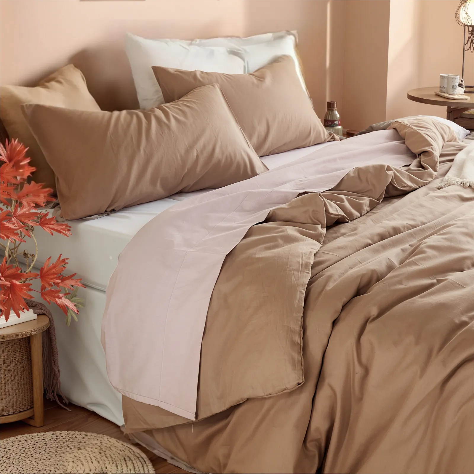 Headboard view of beige camel duvet cover with subtle pink trim, wicker table and red leaves.