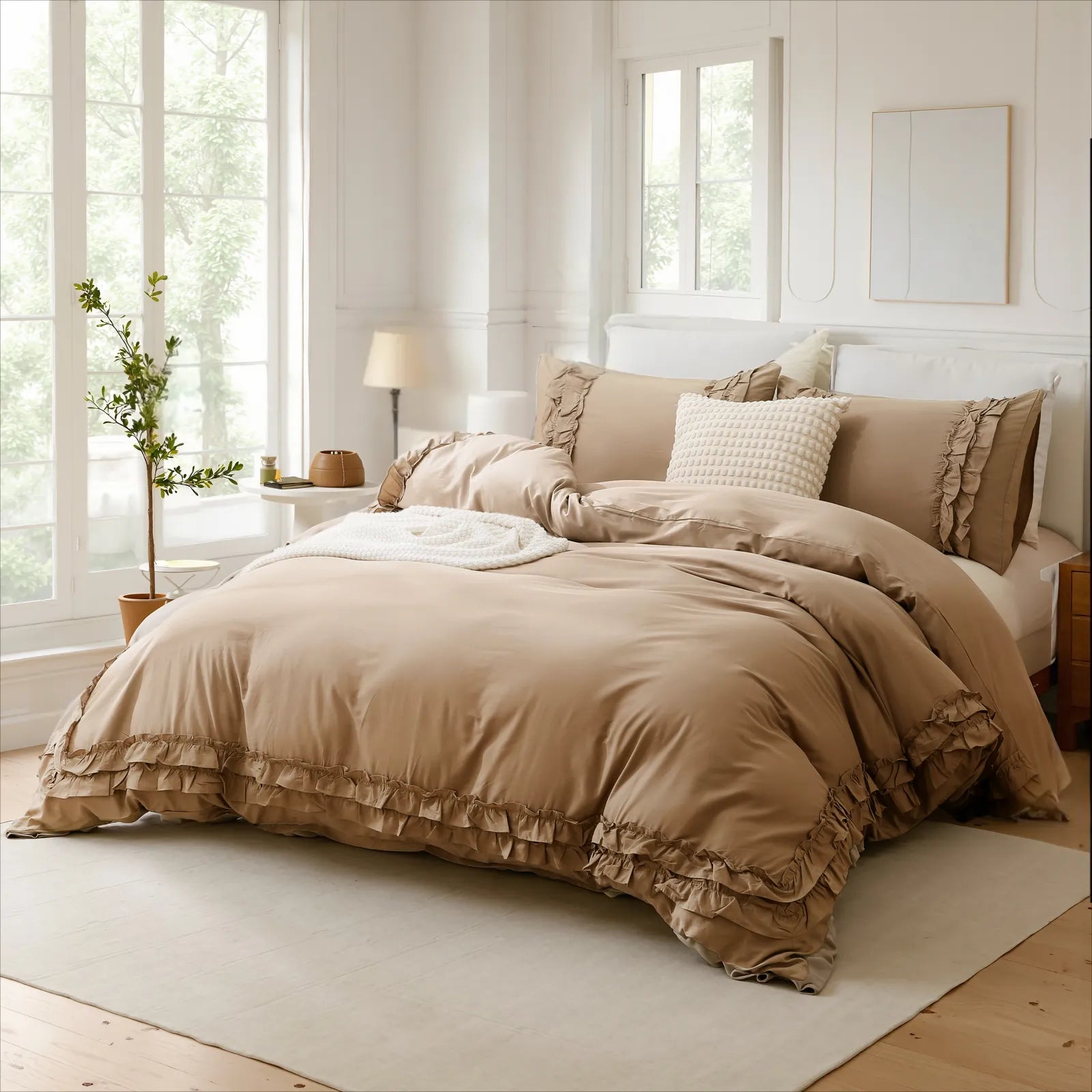 Beige cotton double ruffle duvet cover and pillows on a bed with a checkered pillow, bedside lamp, and large window.