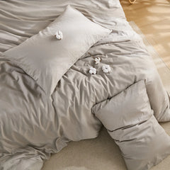 Top down view of beige grey duvet cover on bed with pillow and cotton details
