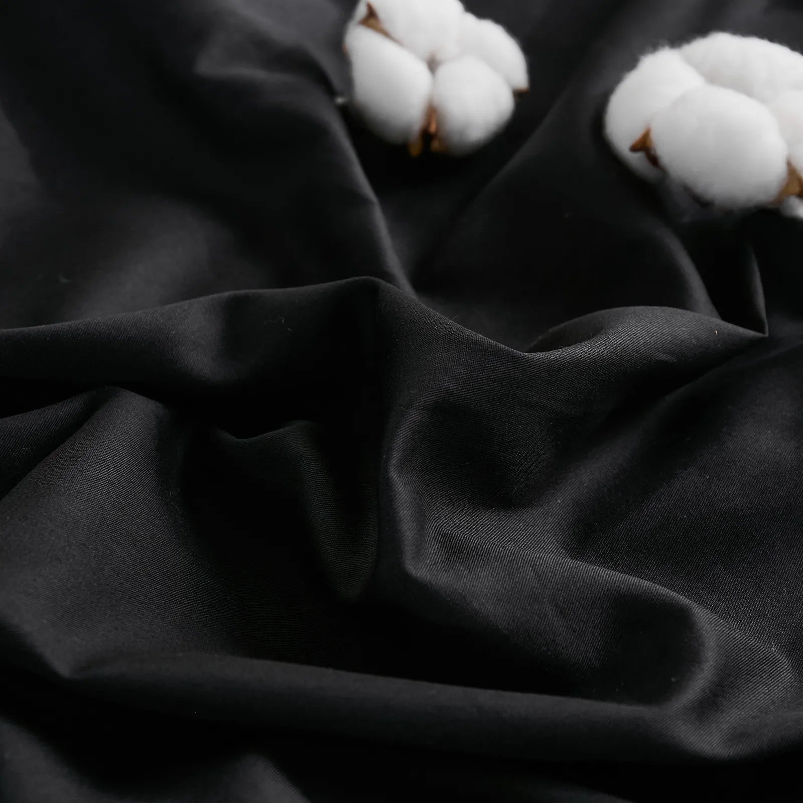 Black duvet fabric texture close-up with two white cotton details