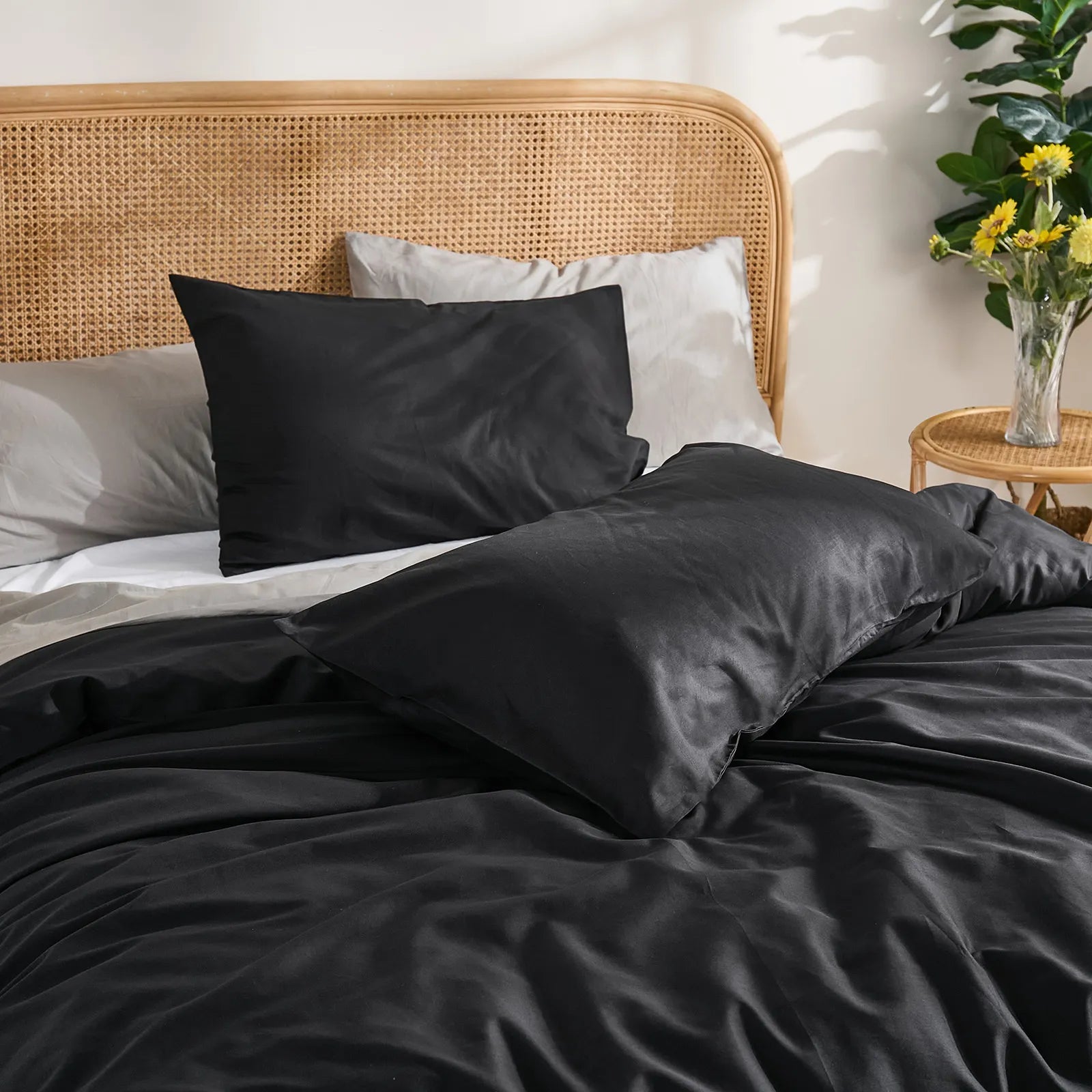 Headboard detail shot of black duvet with brown curtains background, yellow flowers adding color accent.