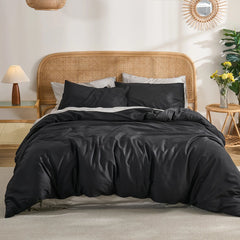 Symmetric bedroom layout with black duvet centered between two woven side tables, circular wall mirror above.