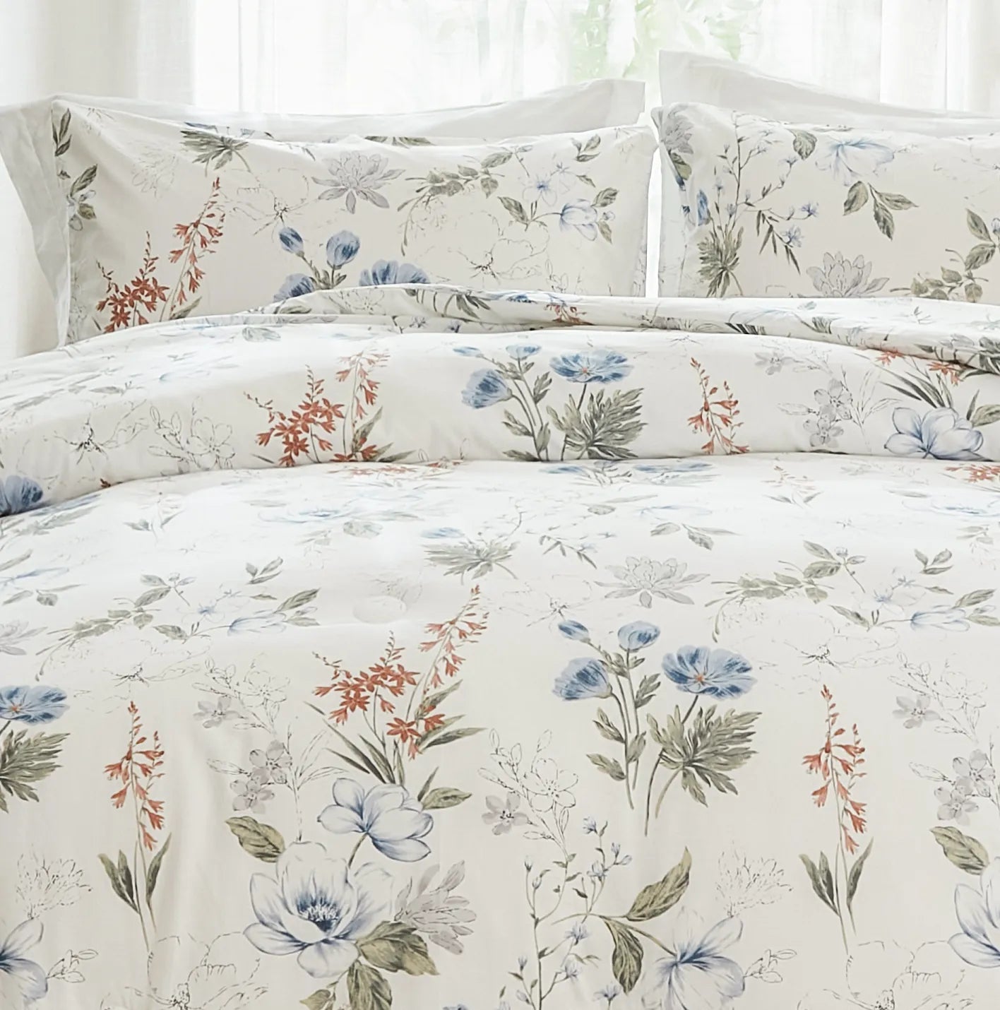 Close-up of the fabric texture of a white comforter with a blue and orange floral pattern.