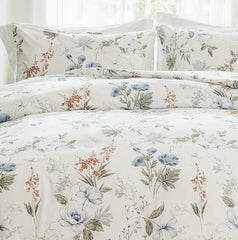 Close-up of the fabric texture of a white comforter with a blue and orange floral pattern.
