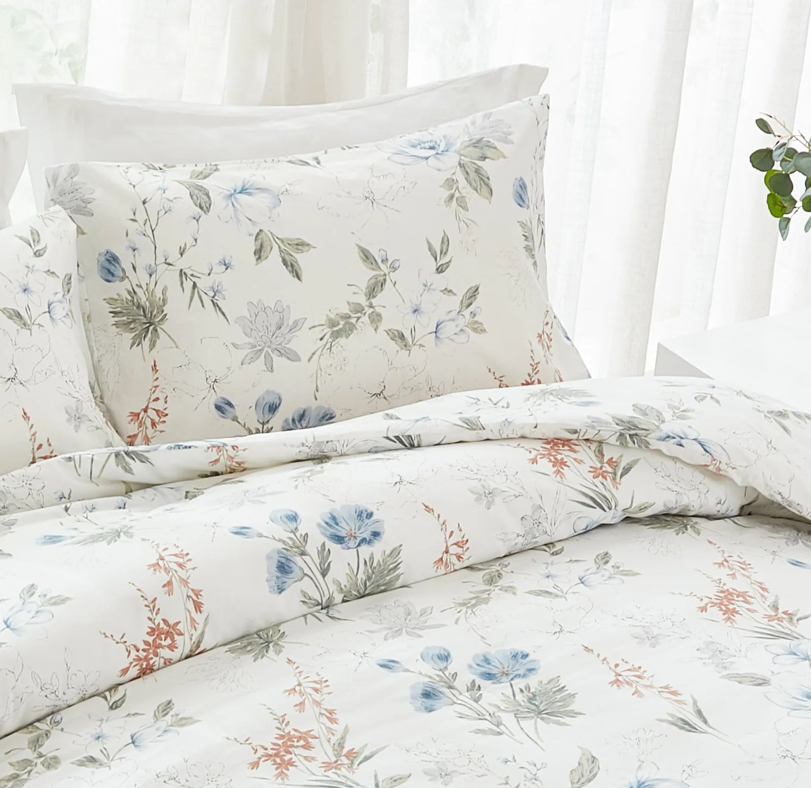 detailed view of the blue floral pillowcases on a bed with striped bedding