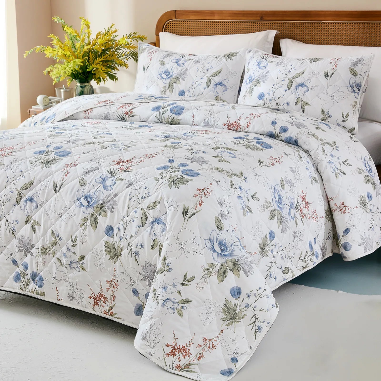Angled view of a bed with a white and blue floral quilt, revealing the full pattern and texture.