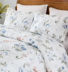 Close-up of the bed, showing the white quilt and pillows with a delicate blue floral pattern.