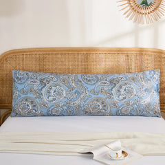 A single long cotton body pillow in a blue paisley print, positioned against a rattan headboard in a bright bedroom setting.