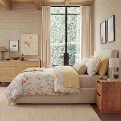 Side view of botanical print bedding set in a bright bedroom with wooden furniture
