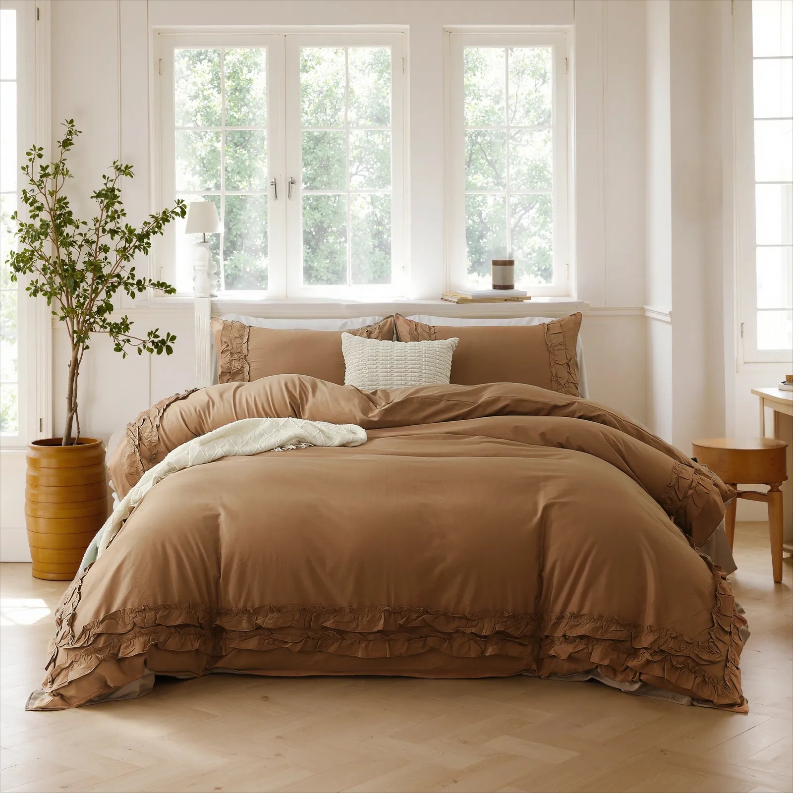 Brown cotton double ruffle duvet cover set with a white pillow, beside a cylindrical planter and a white lamp on a wooden stool.