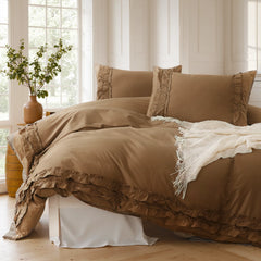 Warm brown cotton double ruffle duvet cover and pillows on a bed with a terracotta vase and green plants near a sunny window.