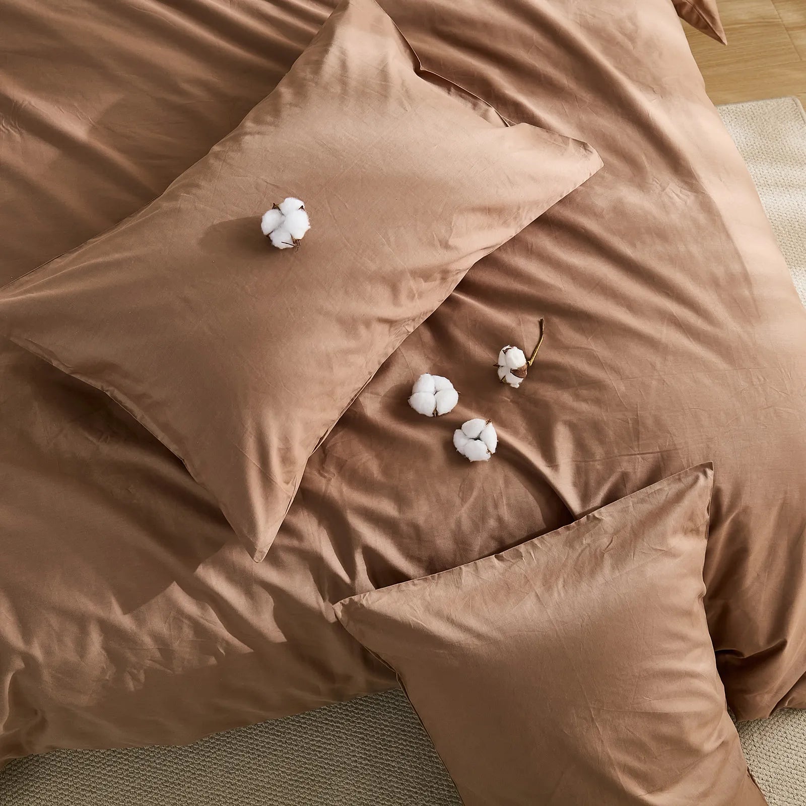 Front view of brown solid duvet with four cotton blooms on bed