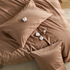 Front view of brown solid duvet with four cotton blooms on bed