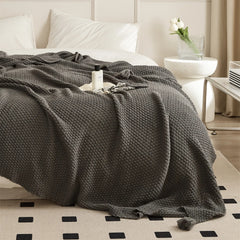 Charcoal Knitted Throw Blanket Draped Bedside with Perfume Bottle