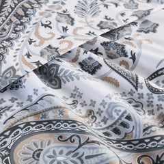 A close-up of a folded cotton bedding set, focusing on the detailed, intricate grey and beige paisley pattern on the fabric.