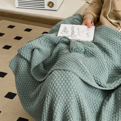 Close-up of Person Using Aqua Knitted Throw Blanket with Tassel Detail