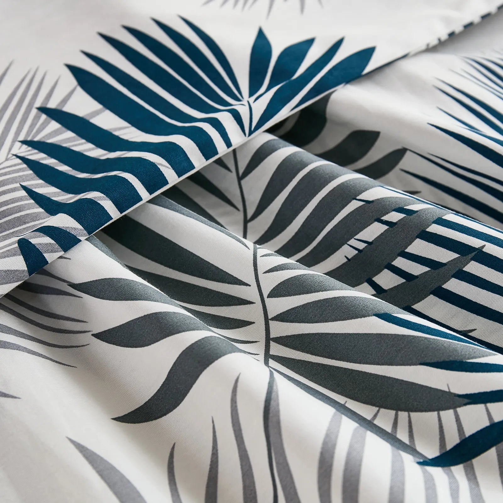 A close-up shot of the cotton fabric of a body pillowcase, highlighting the intricate blue and gray tropical leaf pattern and the soft texture.