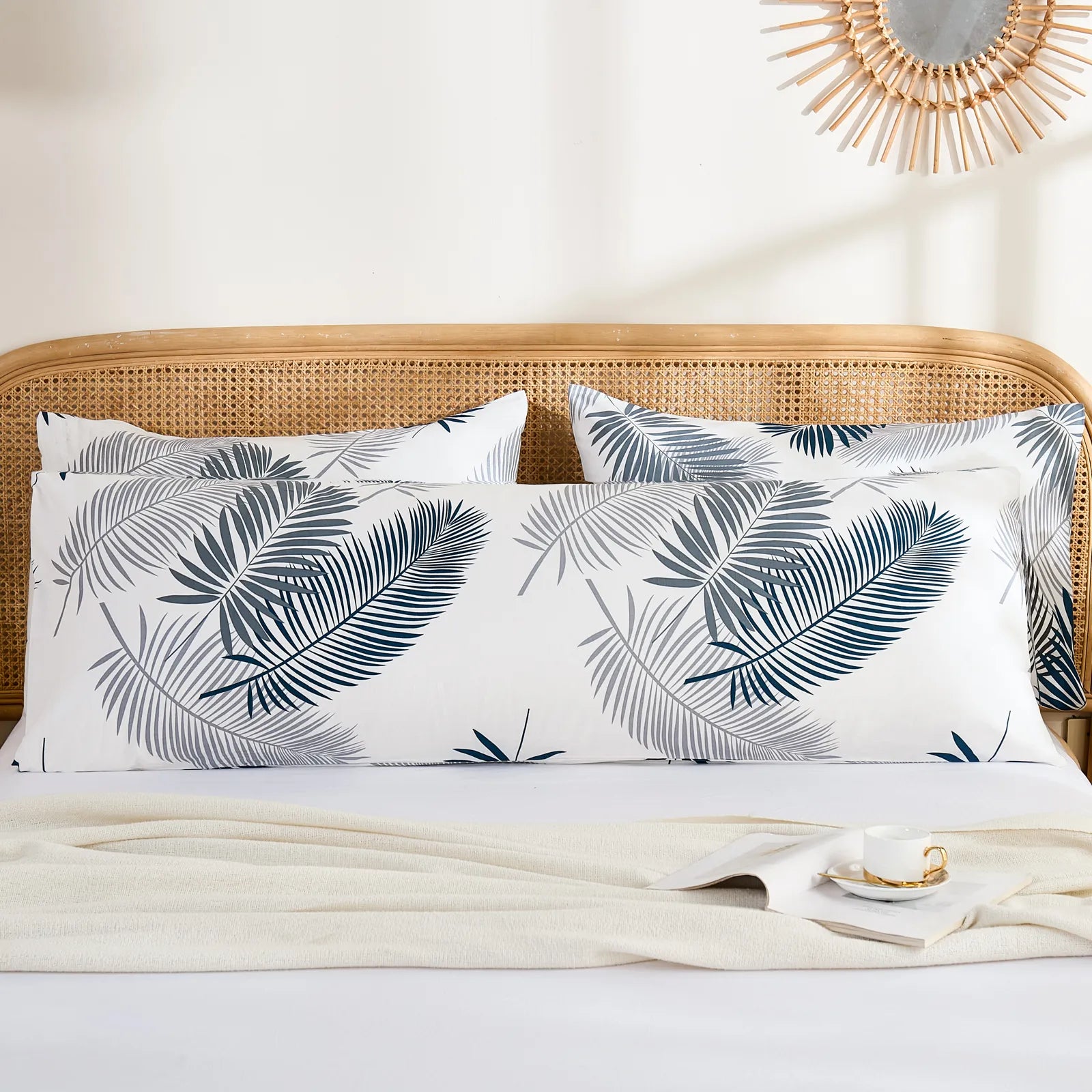 A long cotton palm leaf pillowcase is styled on a bed with two standard-sized matching pillowcases, creating a complete bedding look.