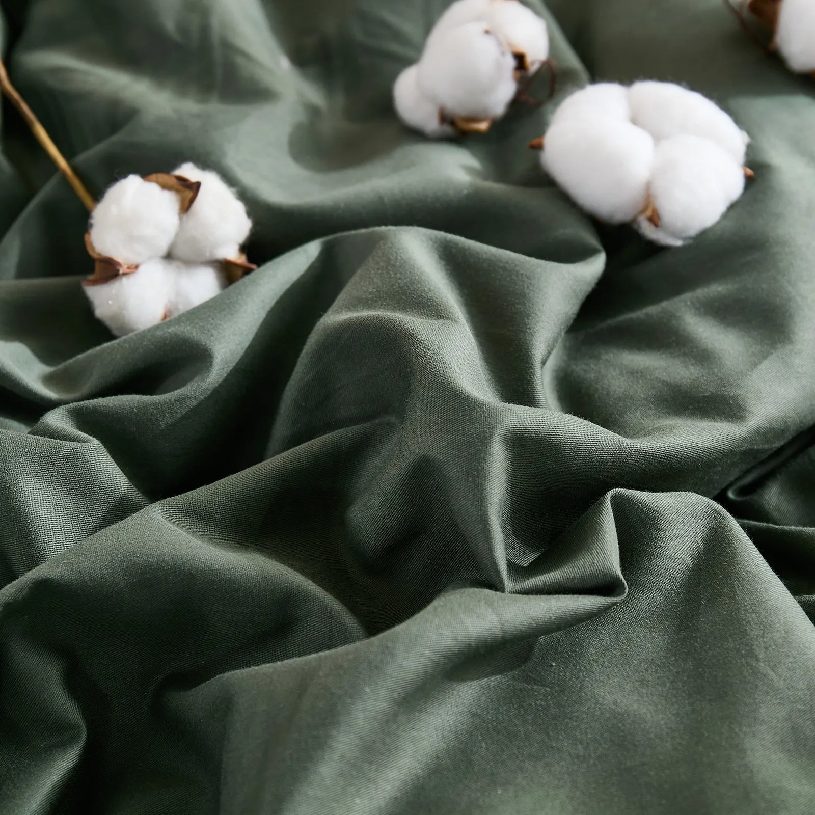 Dark green duvet cover with scattered cotton buds, top angle view