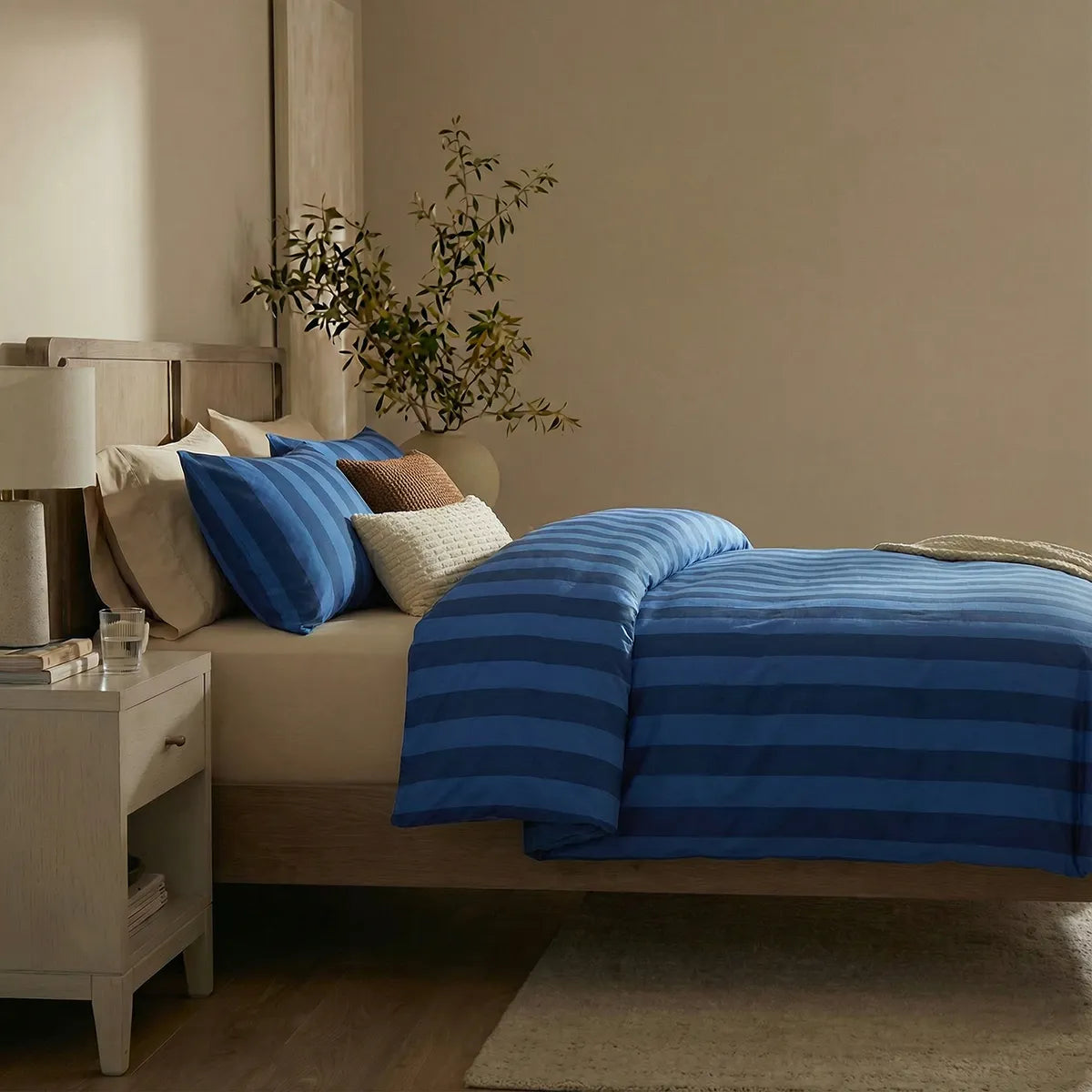 Side view of dark blue and deep blue striped duvet and pillows