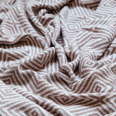 Detailed close-up of the dusty-pink diamond knit throw's texture and soft, flowing folds.