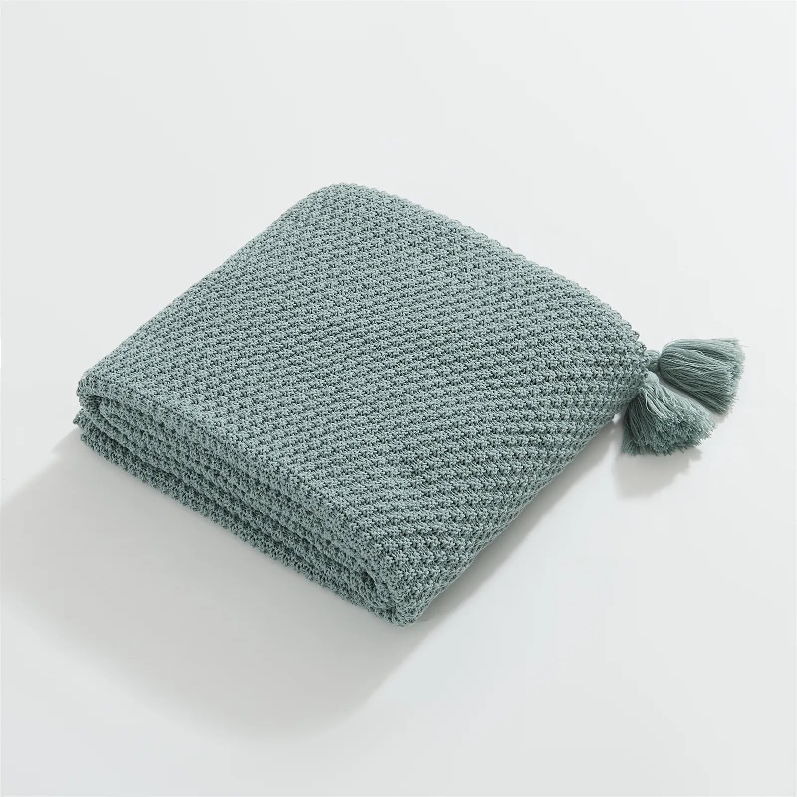 Folded Aqua Knitted Throw Blanket on White Background Showing Tassel