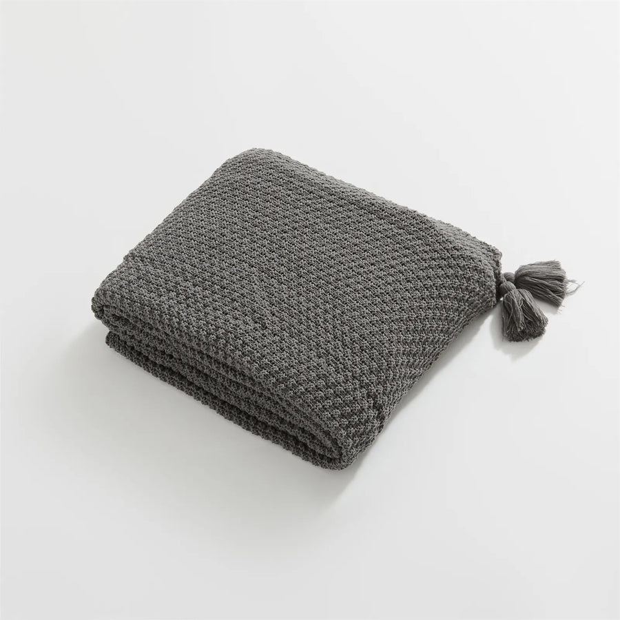 Folded Charcoal Knitted Throw Blanket Showing Tassel on White Background
