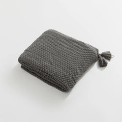 Folded Charcoal Knitted Throw Blanket Showing Tassel on White Background