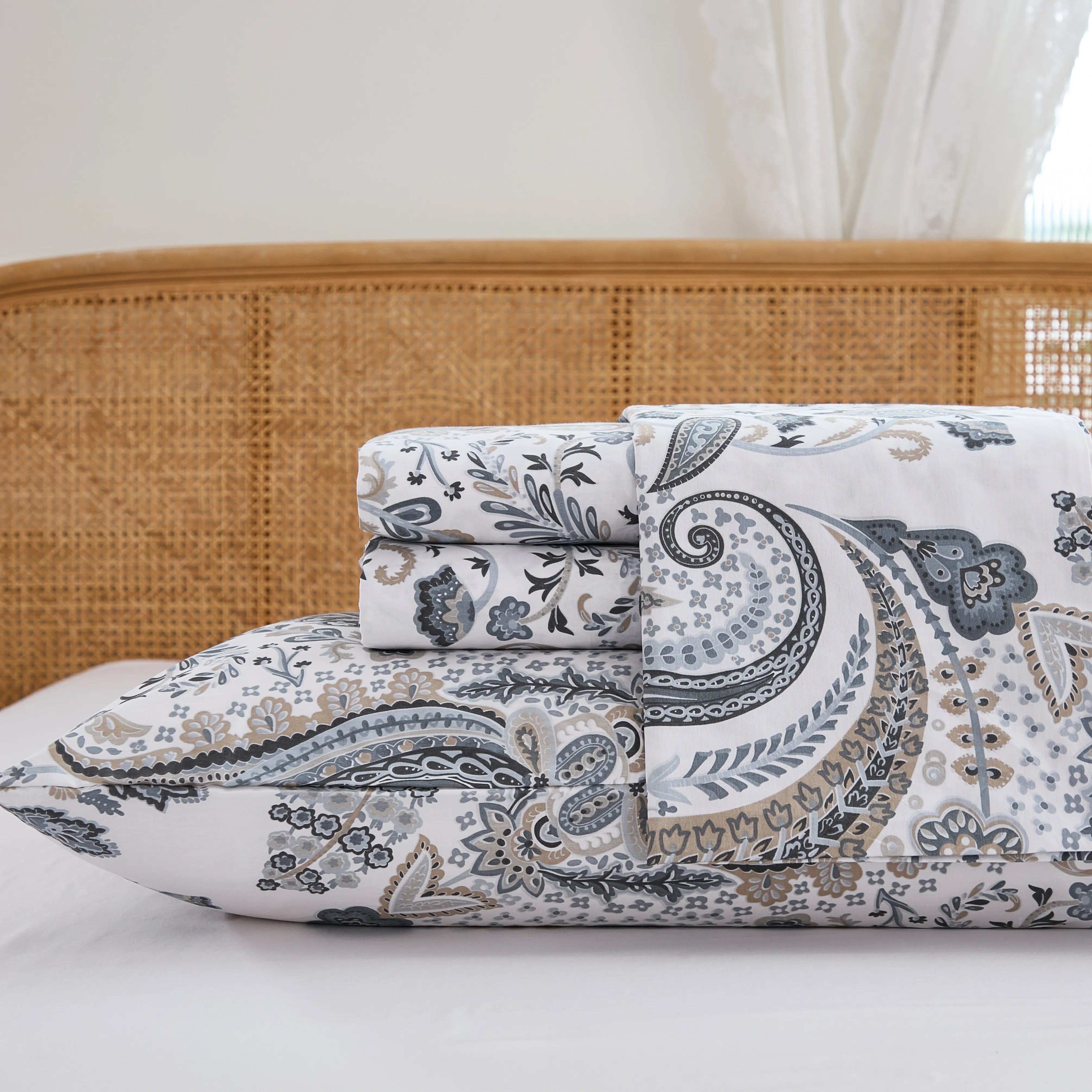 Close up stack of folded cotton neutral paisley fitted sheet and pillowcases studio shot