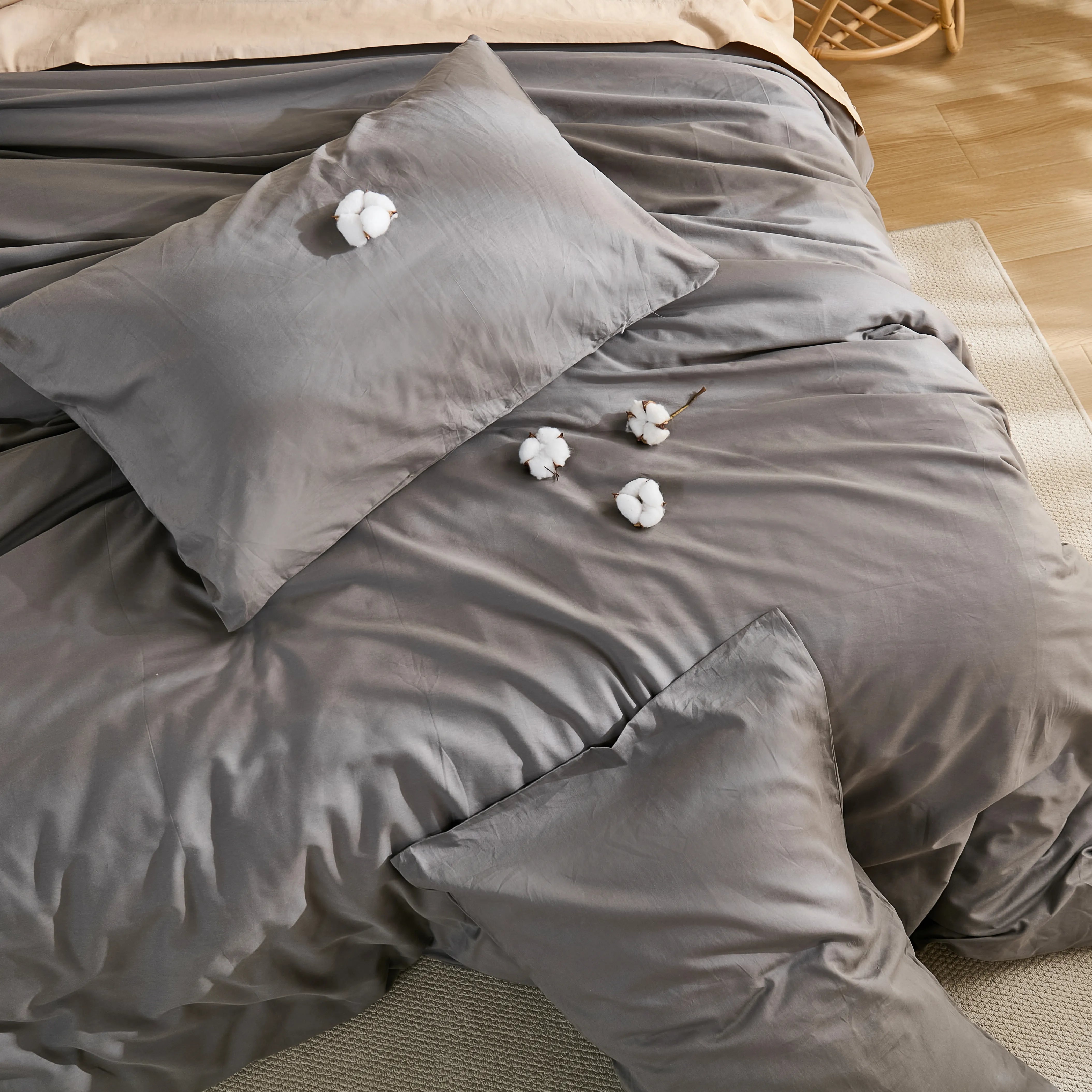 Full view of gray solid duvet with four cotton blooms arranged on bed