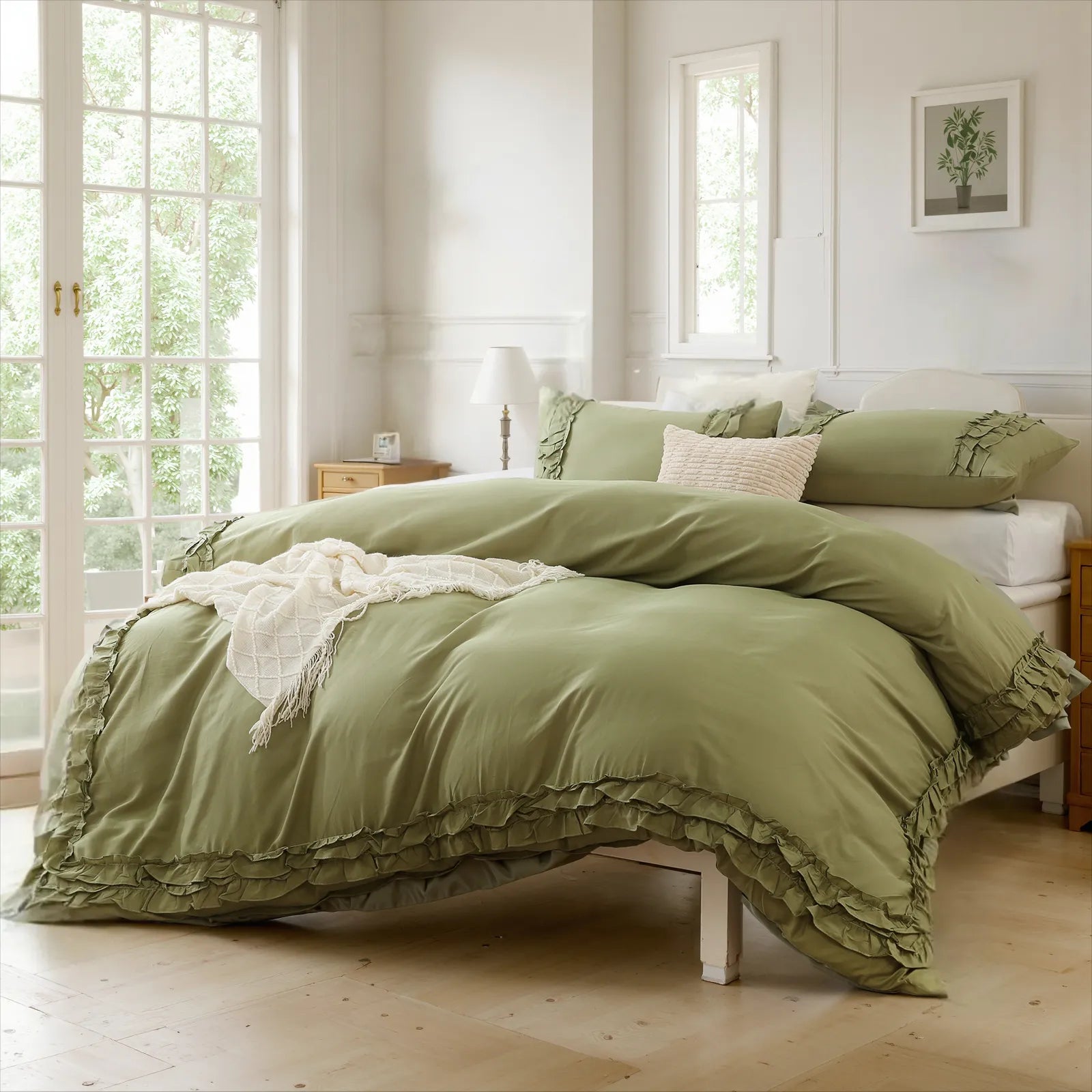 Green cotton double ruffle duvet cover on a white bed frame, with white French doors and a plant print on the wall.