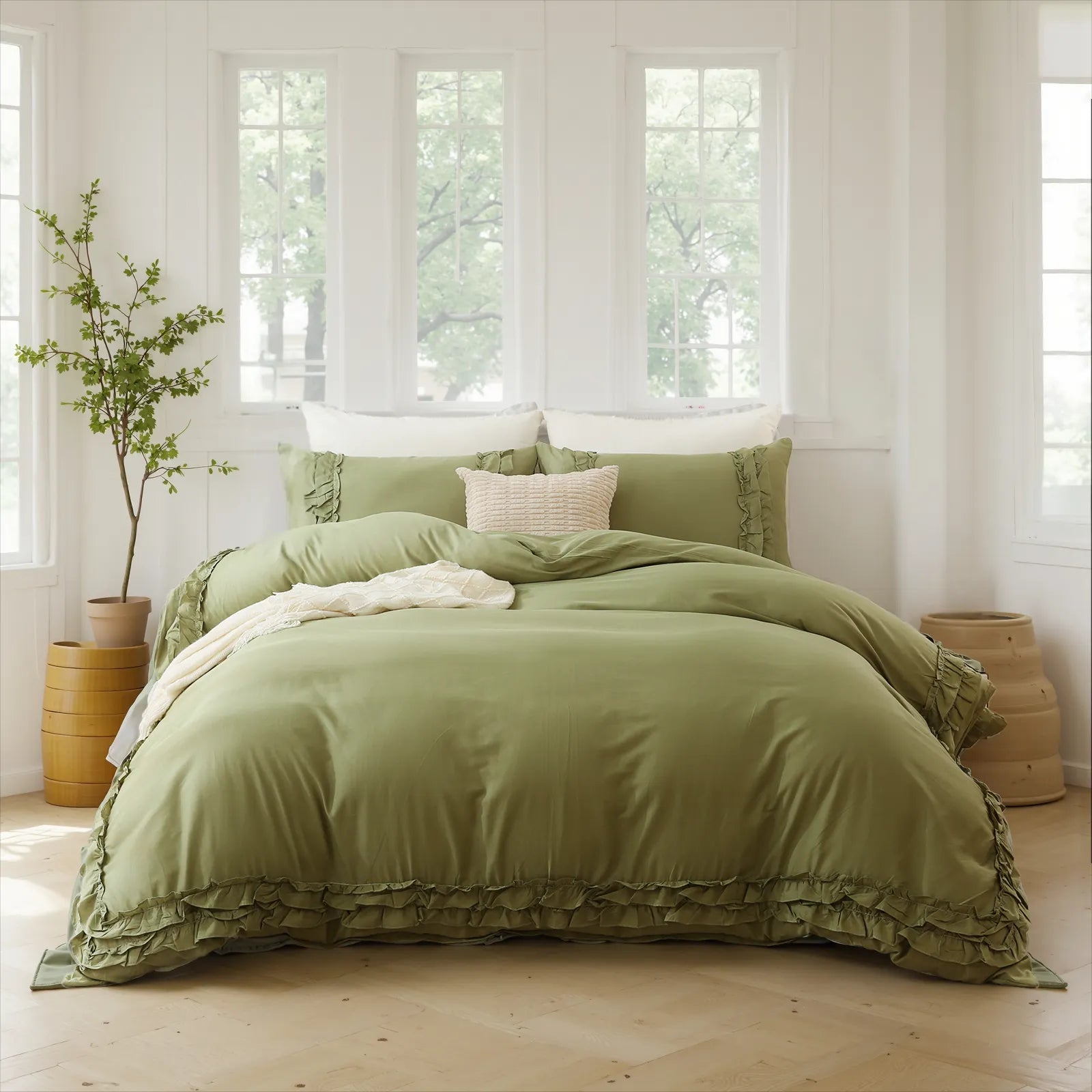 Green cotton double ruffle bedding set on a bed near three large windows, with a plant in a wooden barrel.