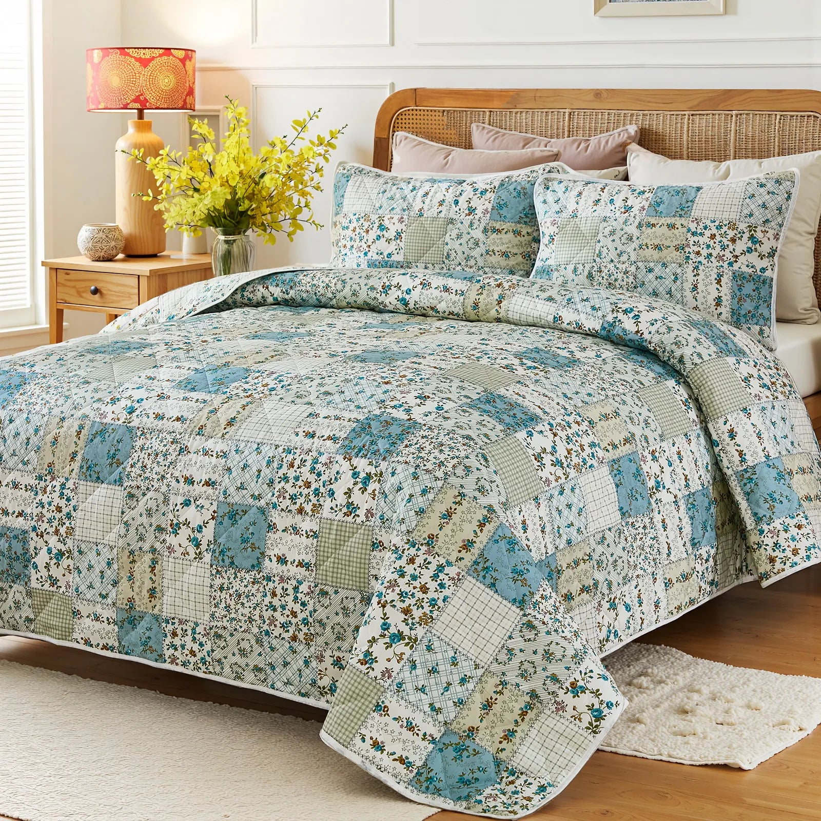 Angled view of a bed with a green and blue patchwork quilt, rattan headboard, and a fluffy white rug.