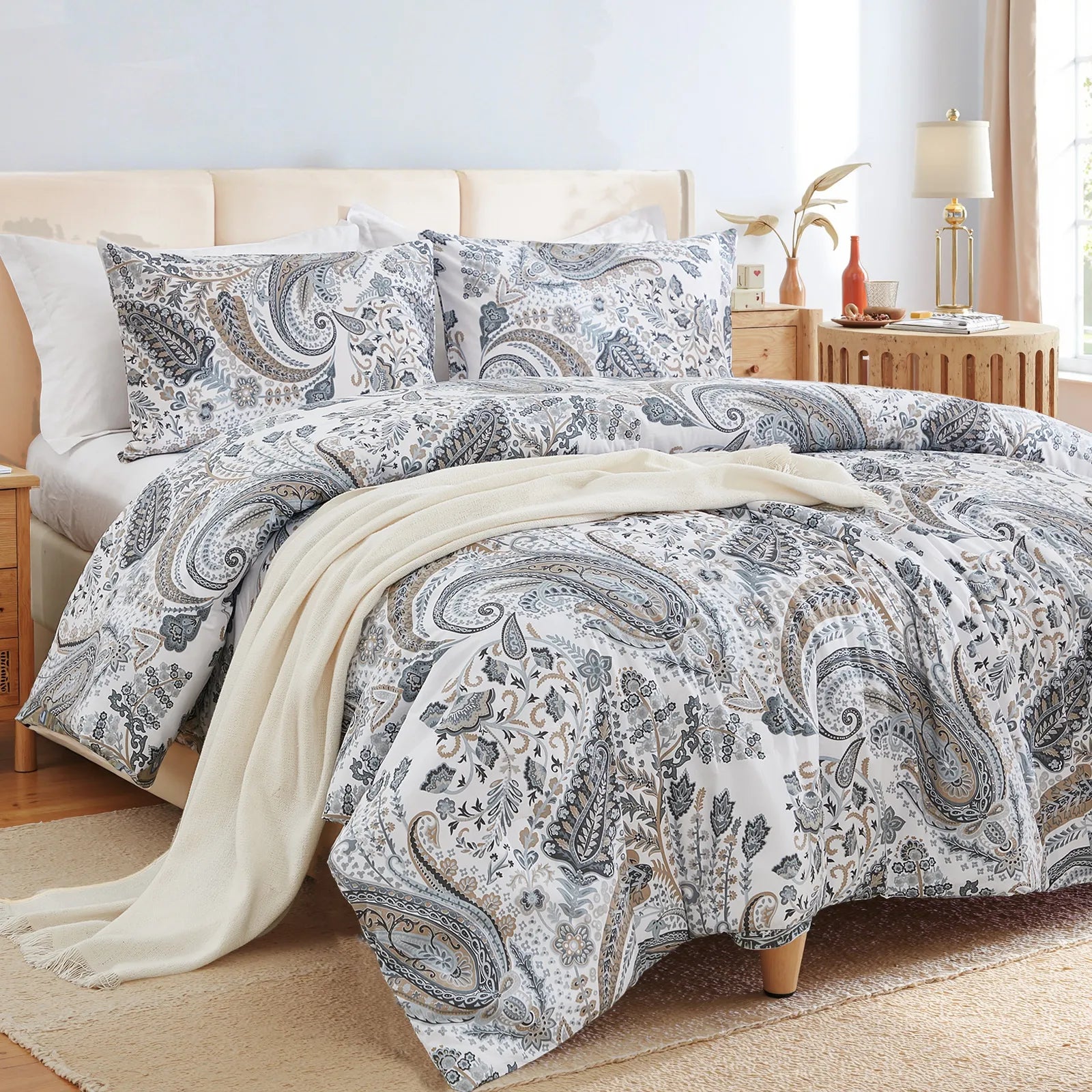 An angled view of the grey paisley comforter set, showing the pillows and decorative items