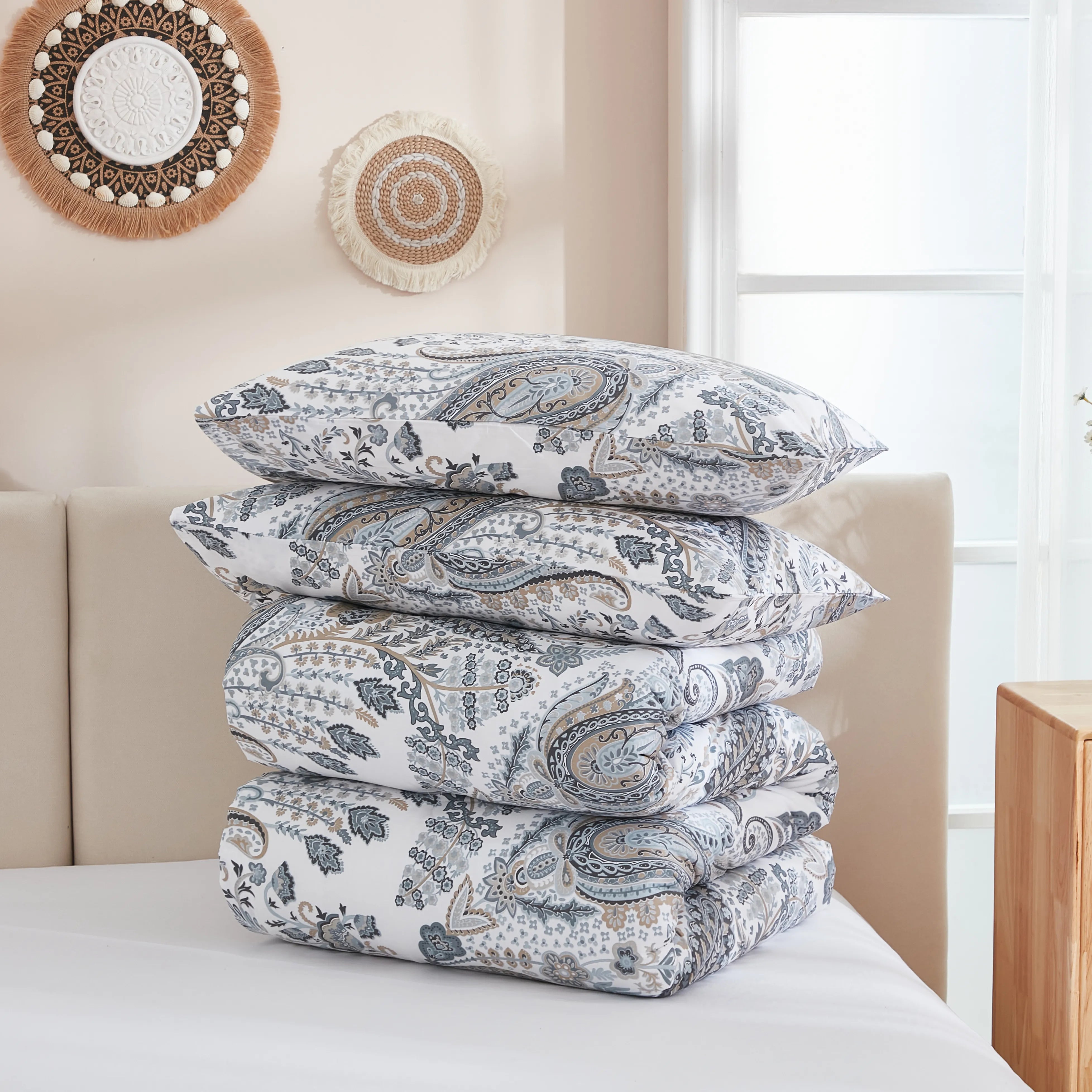 The grey paisley comforter set folded neatly on a bed for display