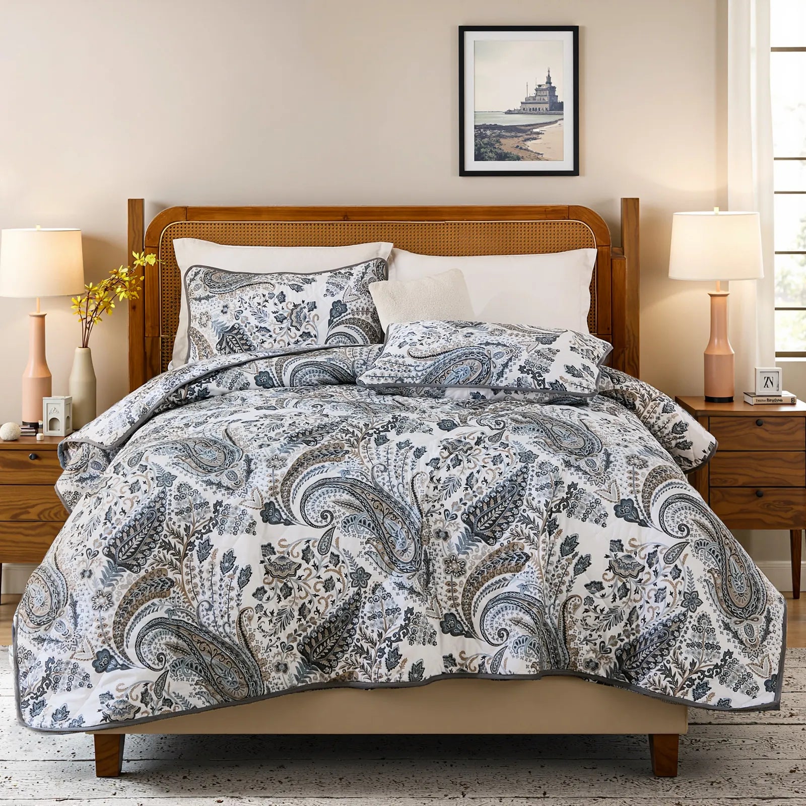 Full view of the grey paisley quilt set styled on a bed in a bright bedroom