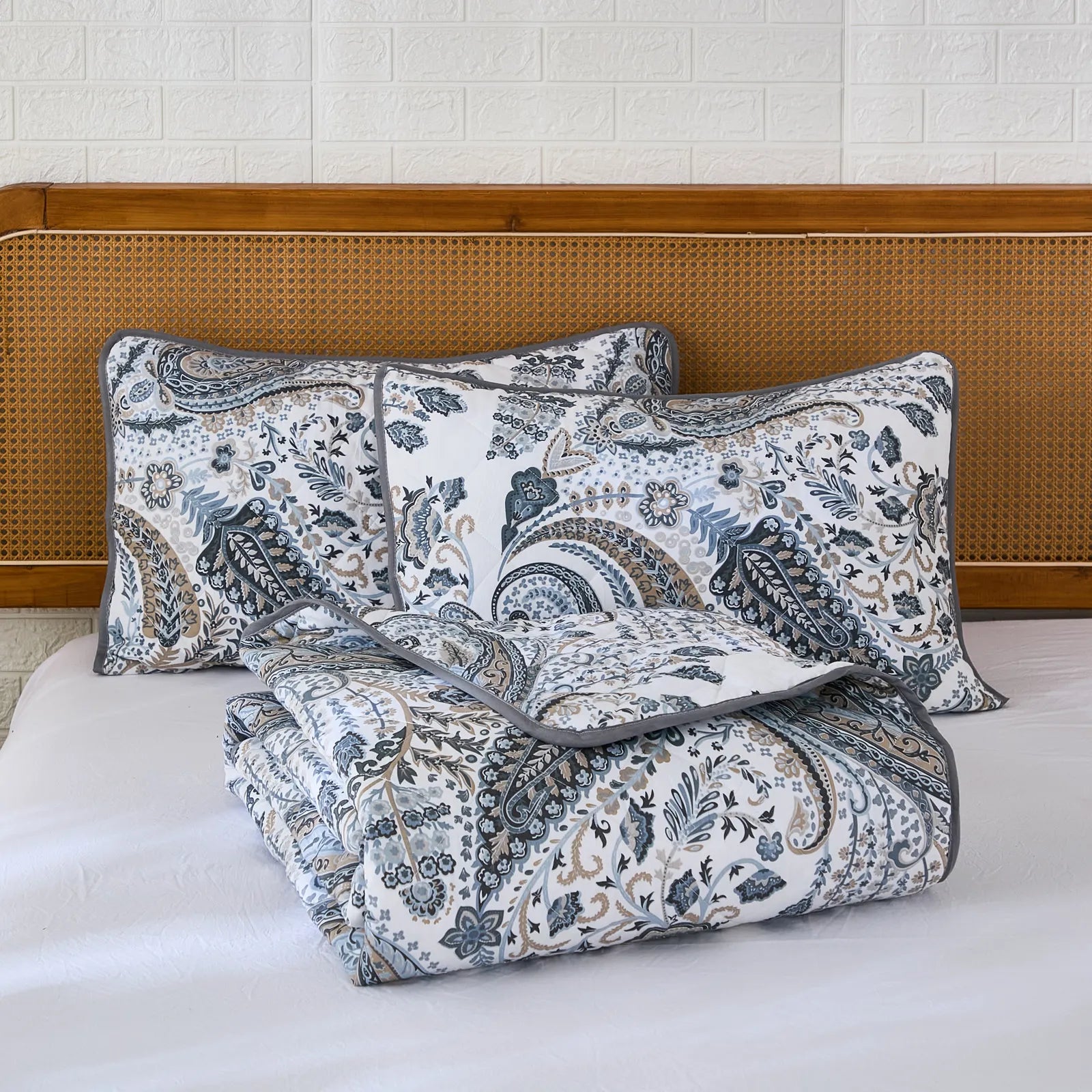 The grey paisley quilt set neatly folded on a bed for display.