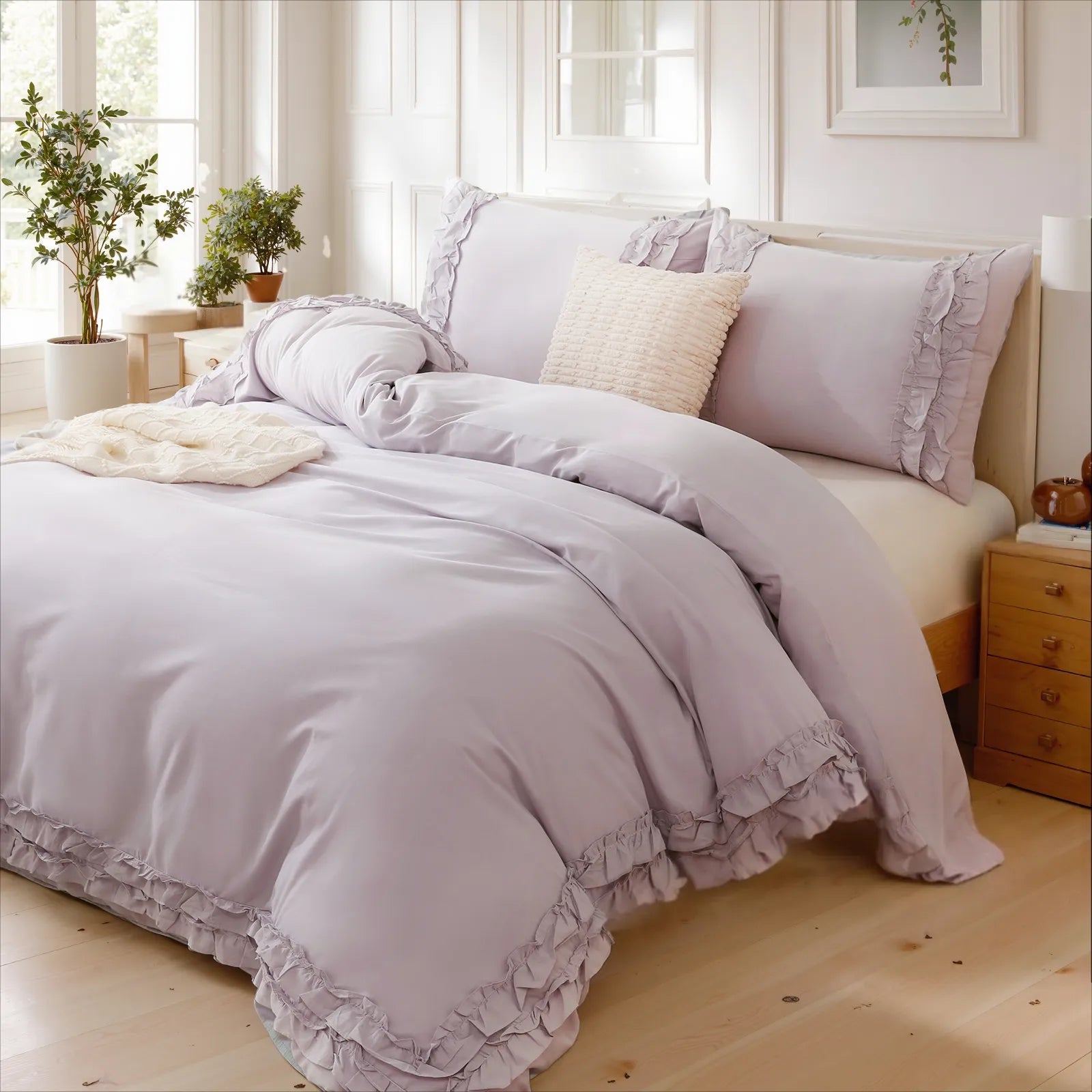 Lavender cotton double ruffle duvet cover on a wooden bed with pillows, a knit throw, and green plants near a window.