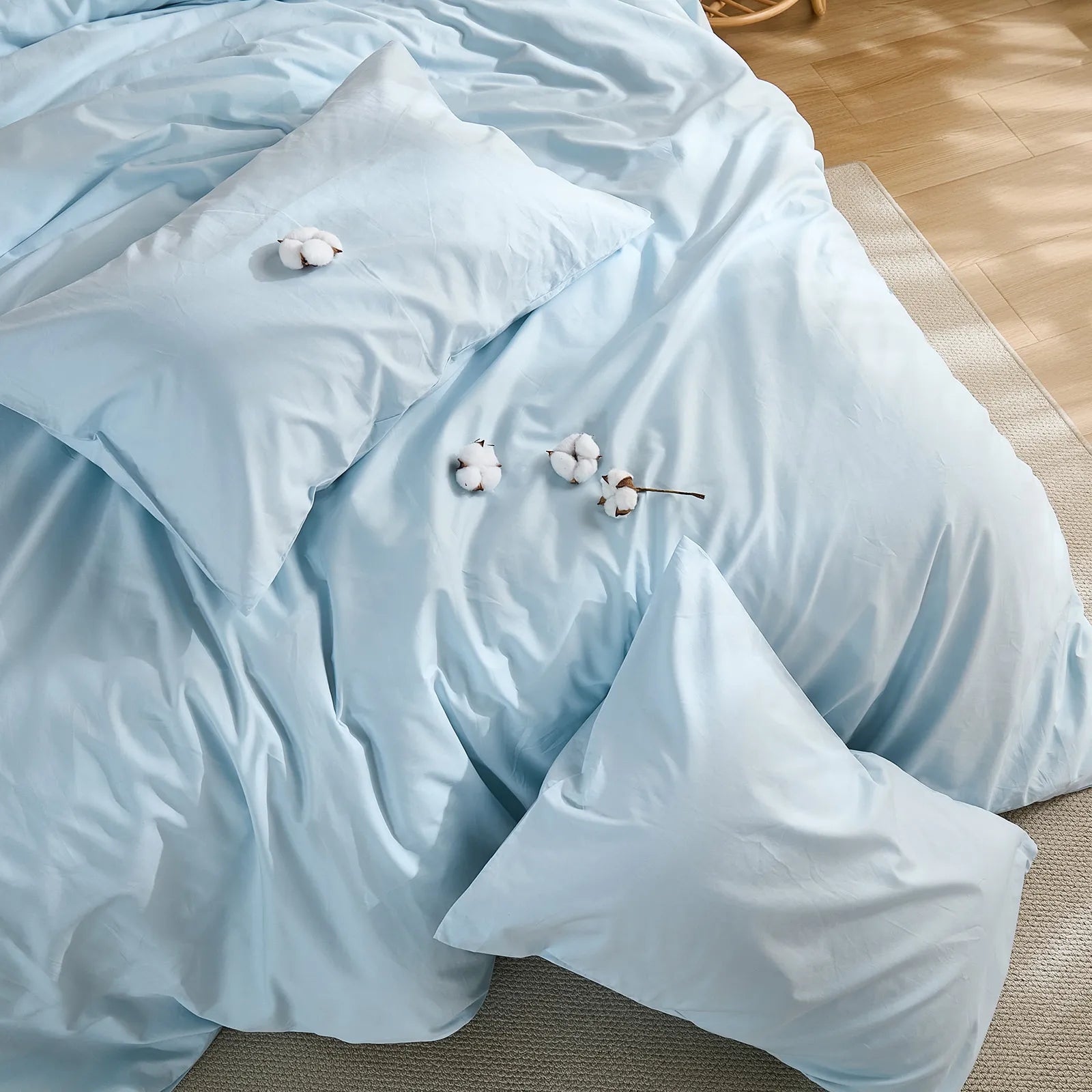 Light blue duvet cover with four cotton clusters and three pillows arrangement