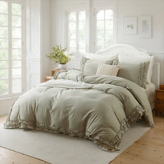 Light gray cotton double ruffle duvet cover on a bed with a white carved headboard, between three large windows.
