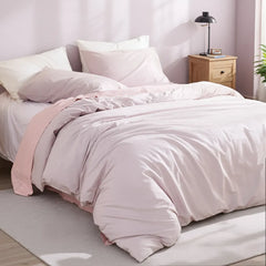 Side view of light purple duvet with matching pillows, green plant accent and harmonious color scheme.