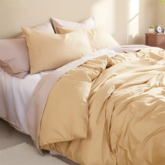 Close-up shot focusing on the layered pillows and light yellow duvet texture.