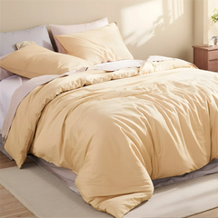 Top down view of light yellow duvet fully covering the bed with multiple pillows.