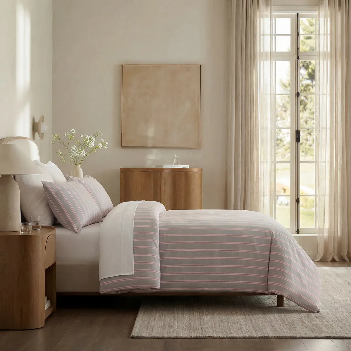Side view of light grey and pink striped duvet and pillows